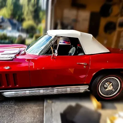 A bright red Corvette with tan convertible top.